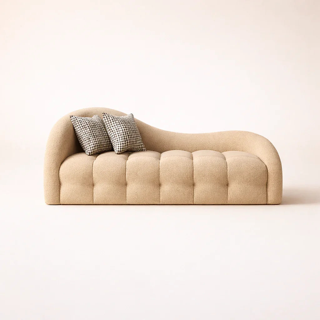 Modern beige curved sofa with tufted upholstery and two plaid accent pillows